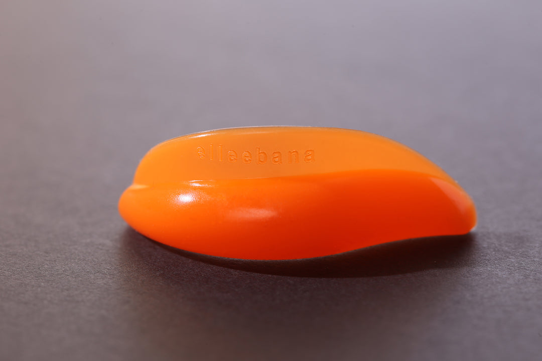 A small orange Elleebana Flex Shields for Lash Lifting sits on top of a black surface, promoting lash lift procedures and Elleebana growth.