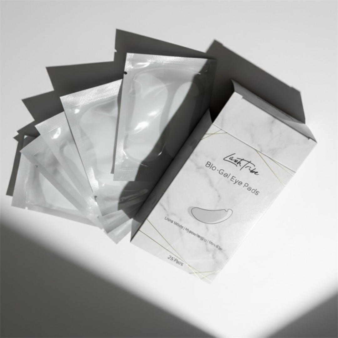 A box labeled "NEW Under Eye BIO Gel Pads" from Lash Tribe is shown with five individual sachets. These pads are safe for sensitive skin and perfect for use during eyelash extension applications.