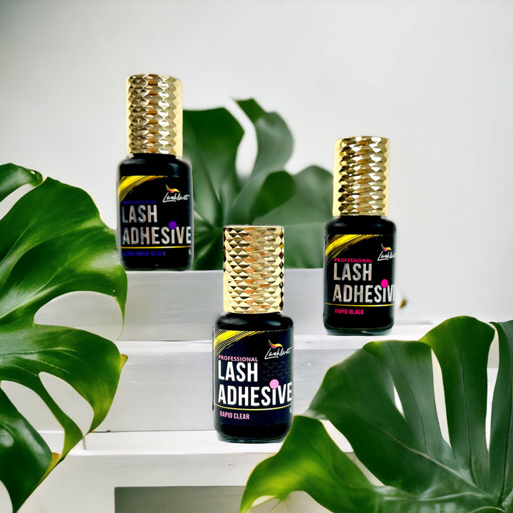 Three bottles of Lash Tribe™️ Lash Glues for Eyelash Extensions sitting on top of a table.