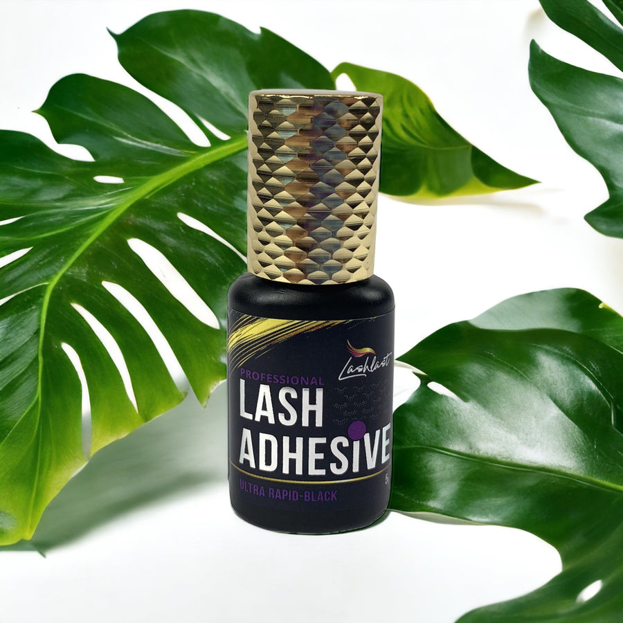A bottle of Lash Tribe Ultra Rapid Black Adhesive, also known as Lash Tribe lash glue for eyelash extensions, resting delicately on top of a leaf.