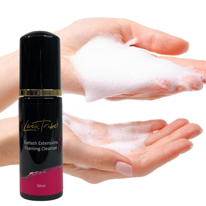 A woman's hand holding a bottle of Lash Tribe Eyelash Extensions Foaming Cleanser for her eyelash extensions.