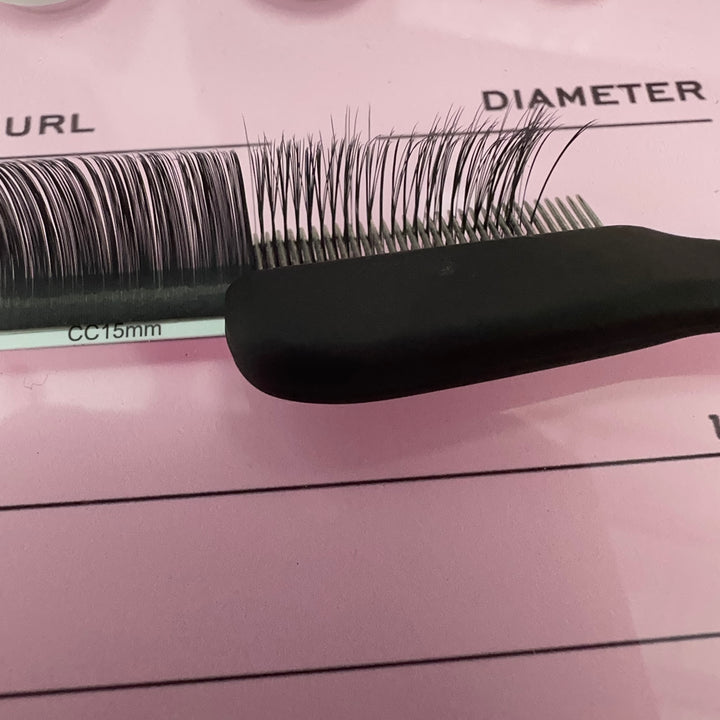 A Lash Comb by Lash Tribe with a pair of black lashes on it.