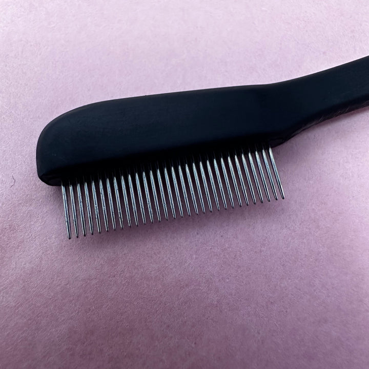 A Lash Comb on a pink background by Lash Tribe.