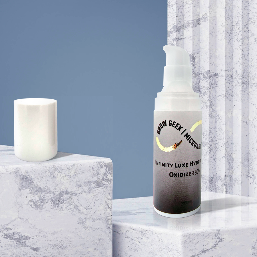A bottle of INFINITY PUMP DEVELOPER OXIDISER 30ML | Lash Lifting | Brow Tinting Developer by Lash Tribe next to a candle on a marble table.