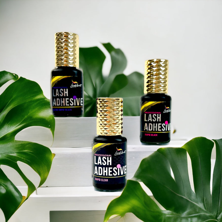 Three bottles of Lash Tribe™️ Lash Glues for Eyelash Extensions sitting on top of a table.