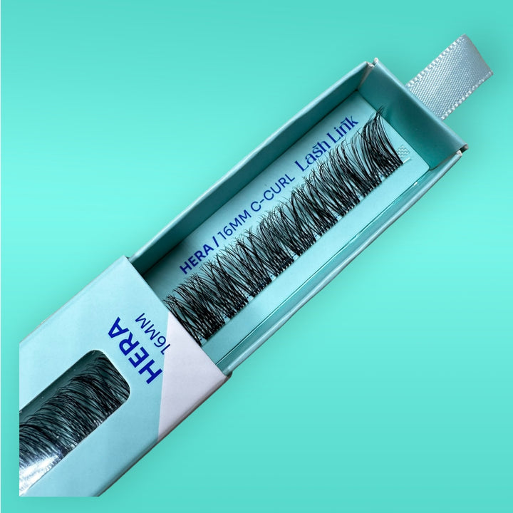 An open package of Lash Link's LIGHT VOLUME | HERA | LASH LINK LASH EXTENSIONS RIBBON in 16MM C-Curl false eyelashes on a light turquoise background, offering light volume lash extensions for a natural look.