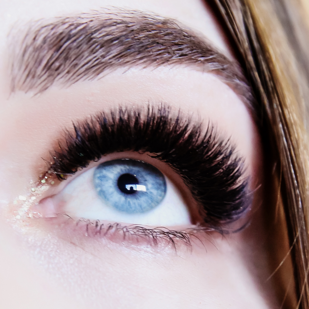 A close up of a woman's eye with long lashes from the Lash Tribe Premium Silk Collection showcasing the 0.07 Russian Volume Lashes | Mixed Tray | Premium Silk | Ultra Black.