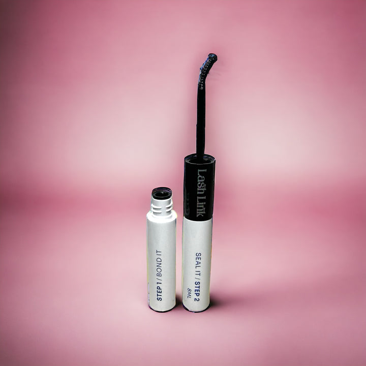 Two tubes of Lash Link Bonder/Sealer Duo on a pink background, with one open showing a curved applicator brush, ideal for achieving salon-quality lash extensions at home.