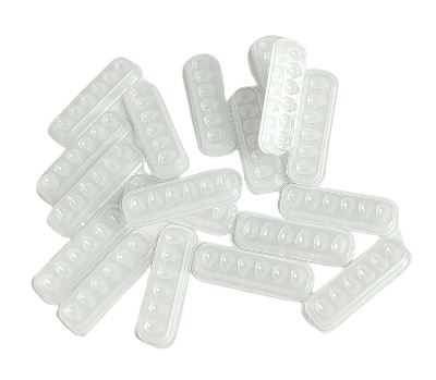 A collection of Lash Tribe Self Adhesive Mini Eyelash Glue Trays, resembling disposable glue trays with multiple round cavities, is scattered on a white background.