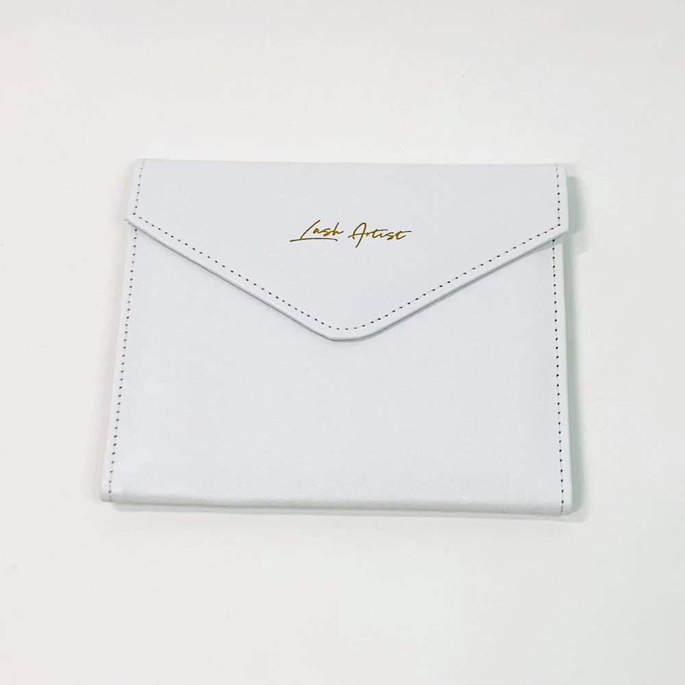 A Lash Tribe Tweezer Envelope with gold lettering on it.
