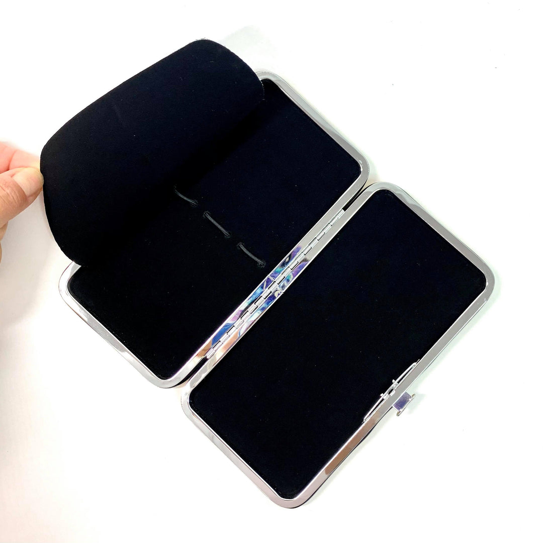 a person's hand is holding a black Lash Tribe Magnetic Tweezer Case.