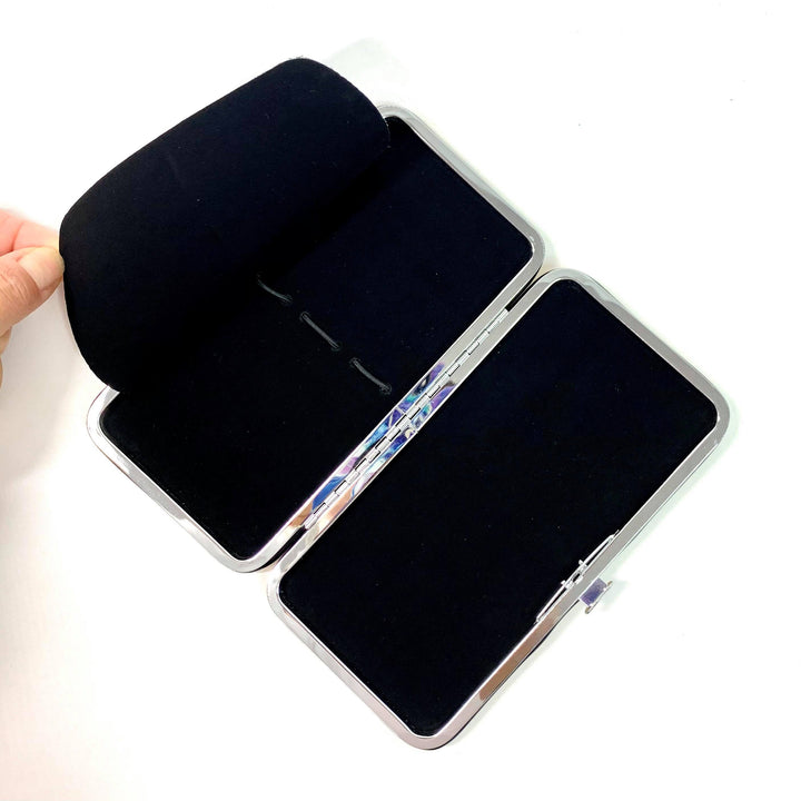 a person's hand is holding a black Lash Tribe Magnetic Tweezer Case.