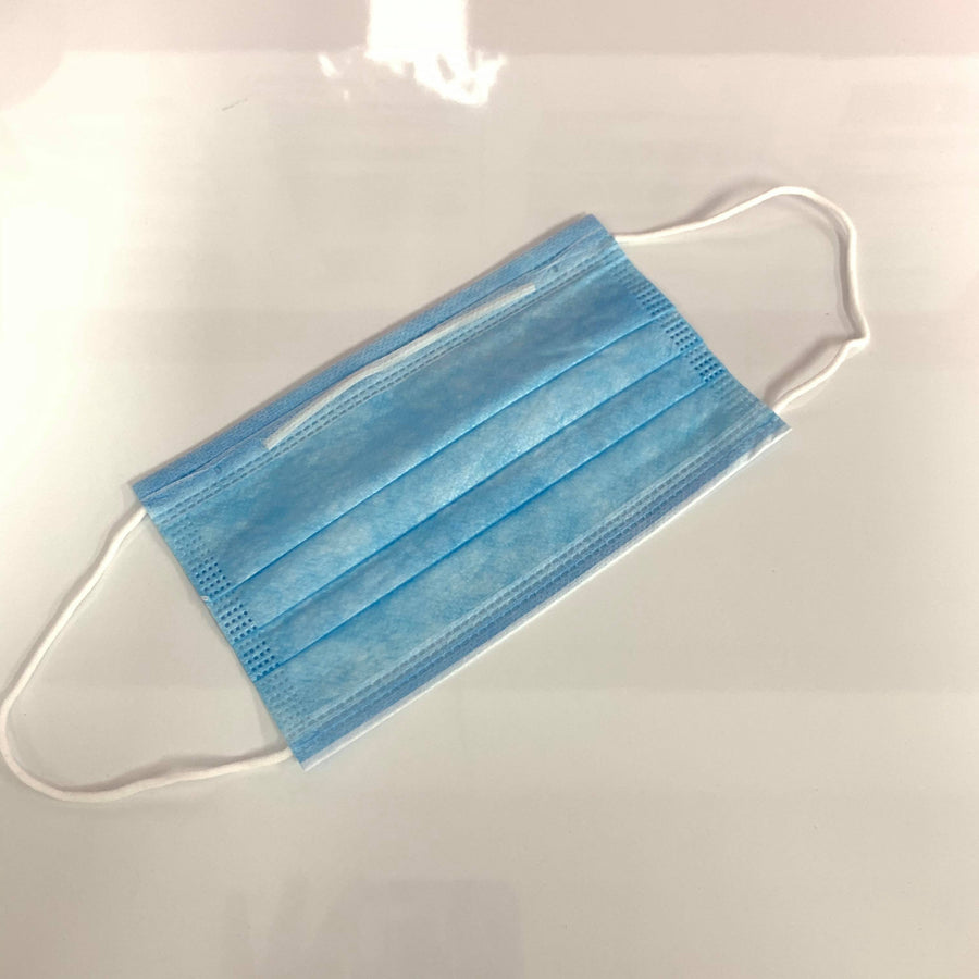 A Lash Tribe blue Surgical Face Mask on a white surface.