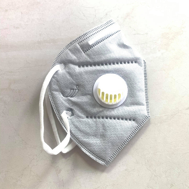 a grey KN95 Medical Grade Mask with Valve from Lash Tribe with a yellow button on it.