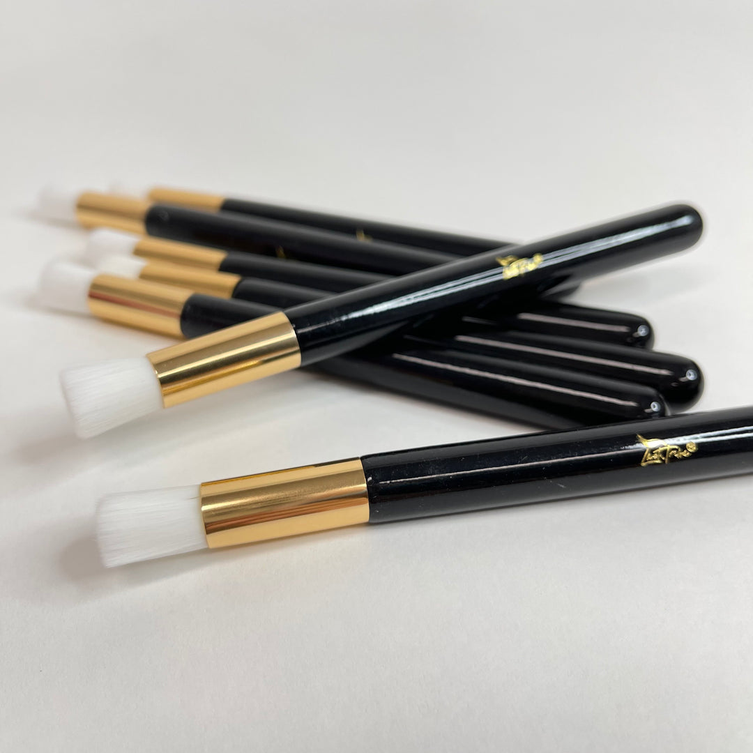 Five Lash Tribe black and gold Cleansing Brushes for Eyelash Extensions on a white surface.