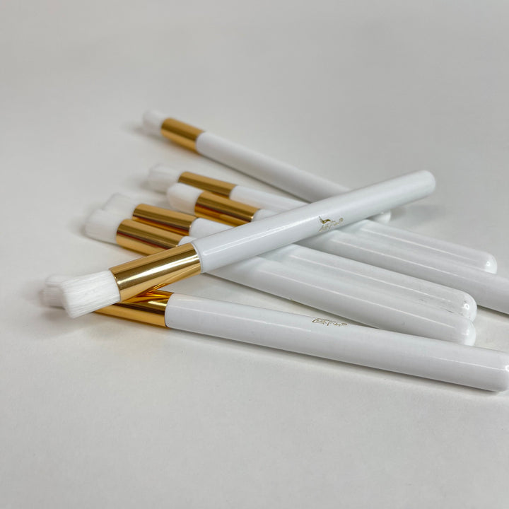 Five Lash Tribe white and gold cleansing brushes for eyelash extensions on a white surface.