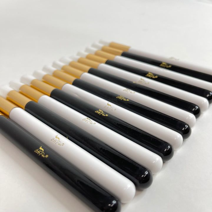a group of Lash Tribe black and gold Cleansing Brushes for Eyelash Extensions on a white surface.