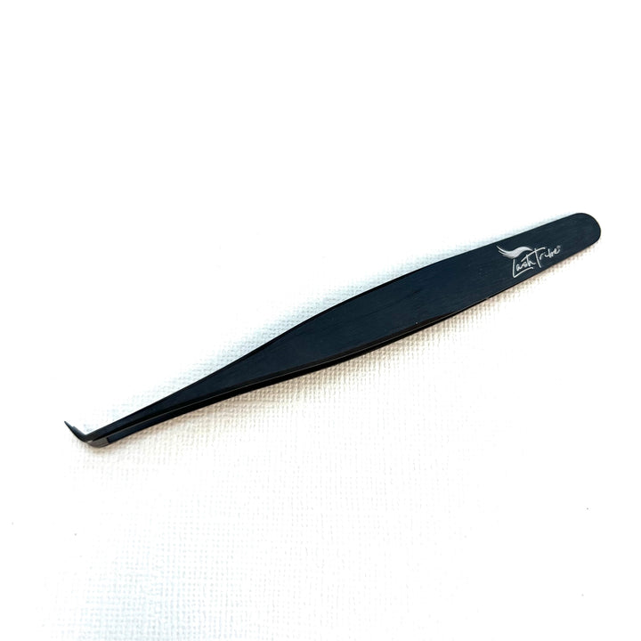 a small black Nano Fibre Tip | Volume Tweezer - Black Beauty 2 on a white surface. (Brand: Lash Tribe)
