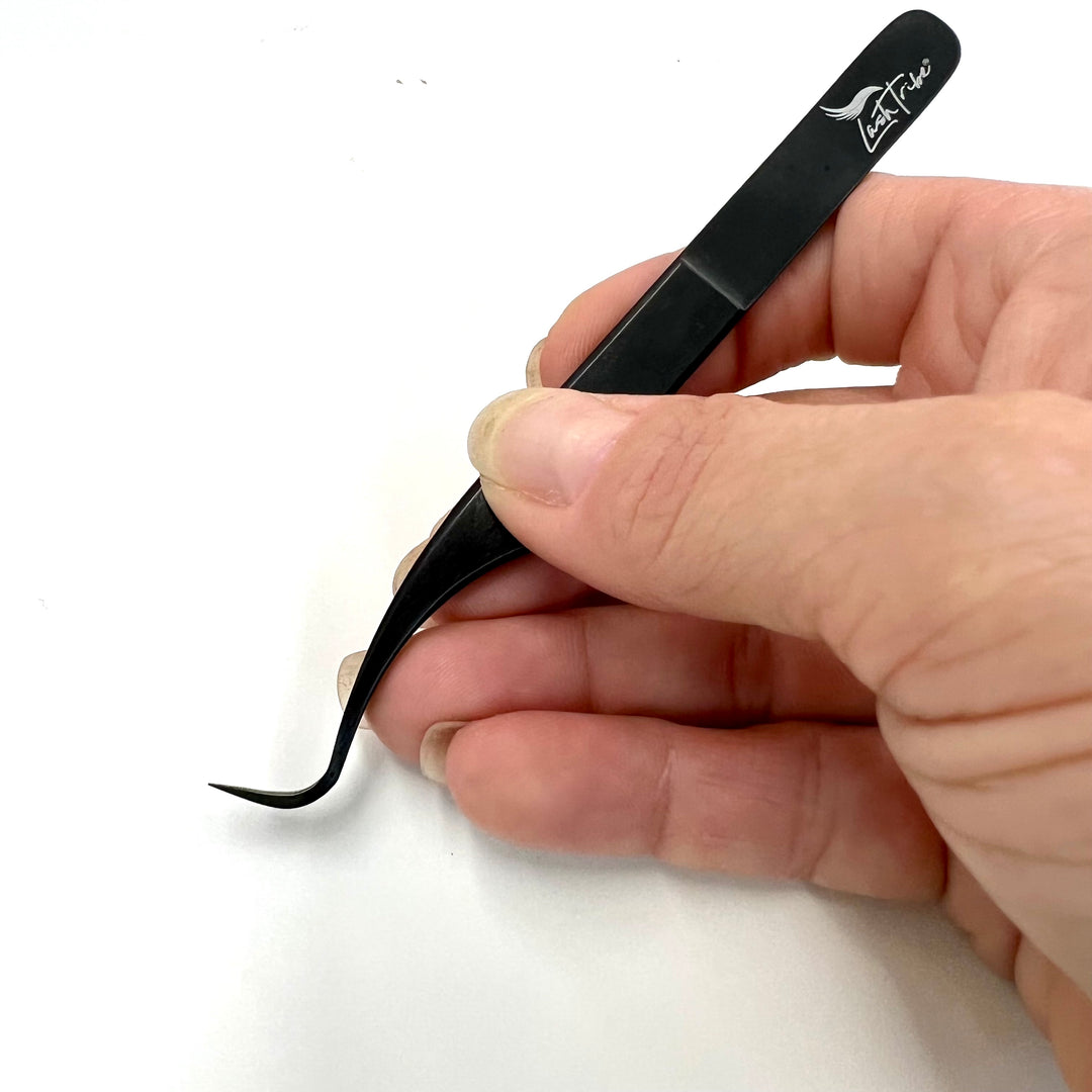 a person holding a small black Nano Fibre Tip | Volume Tweezers- Black Beauty 1 on a white surface by Lash Tribe.