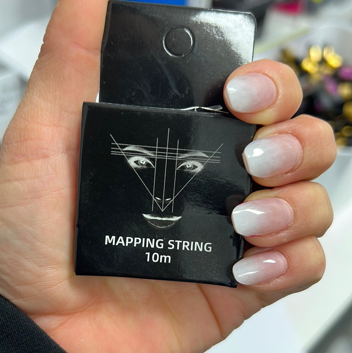 a person holding up a box of Lash Tribe Brow Mapping String.