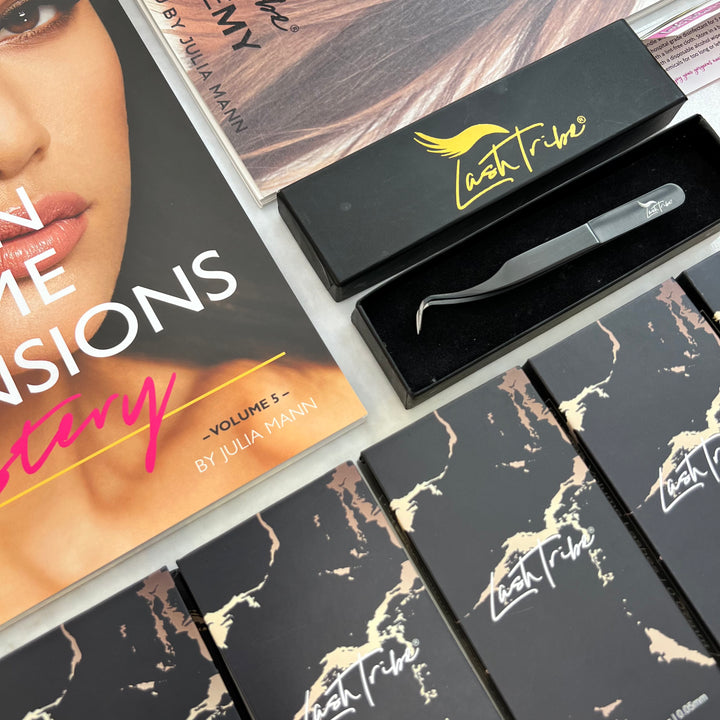Assorted cosmetic products including the Lash Tribe Volume Eyelash Extension Starter Kit and application tools displayed on a table, featuring branded packaging.