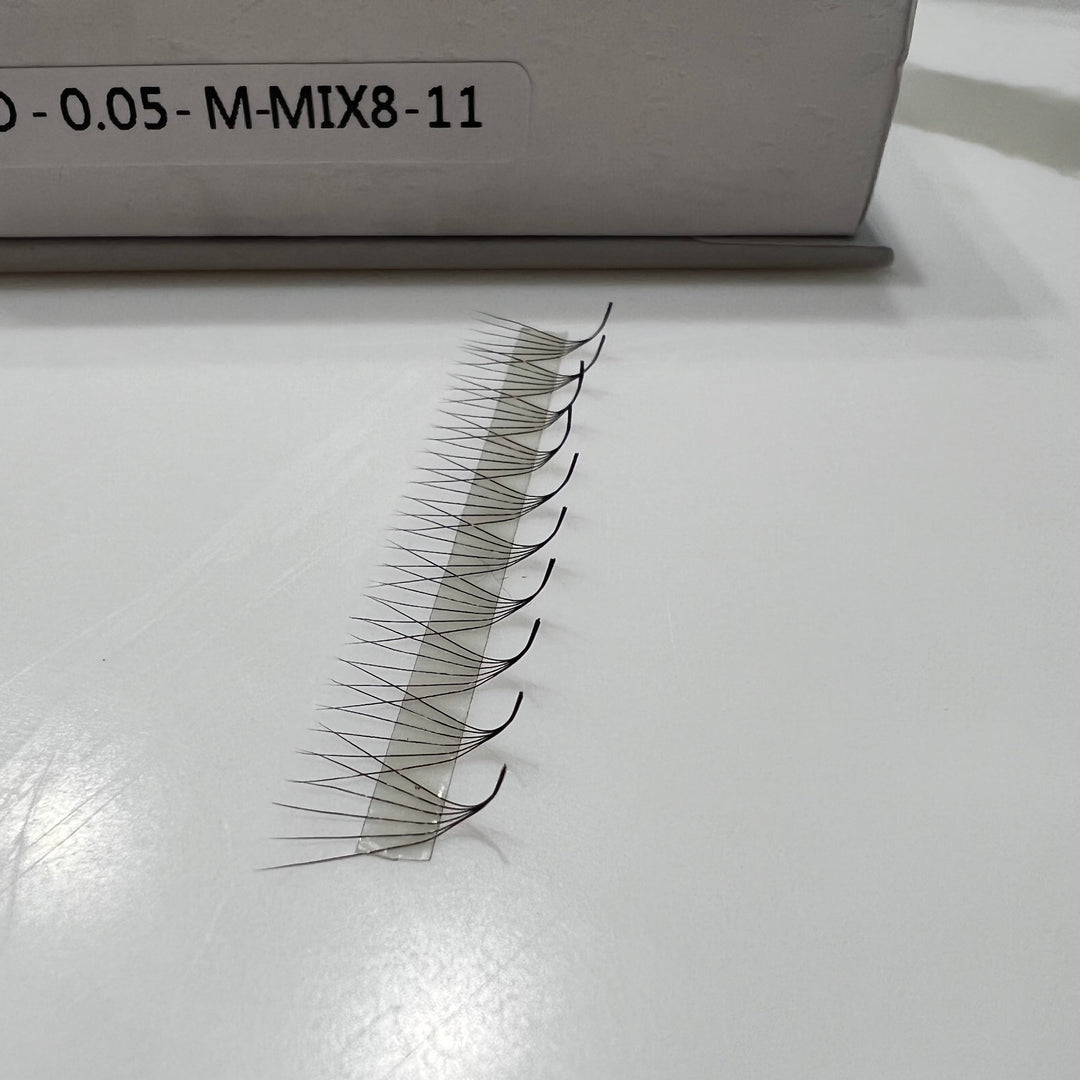 A pair of Lash Tribe Ultra Speed Premade Volume Fans | Long Stem | Ultra Black false eyelashes on a table next to a box.