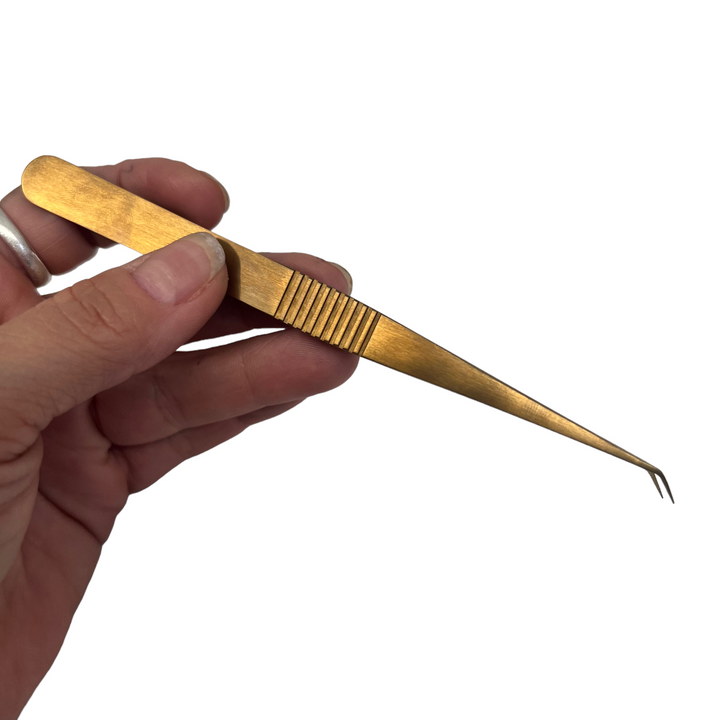 a person holding Lash Tribe New Angled Isolation Tweezers on a white background.