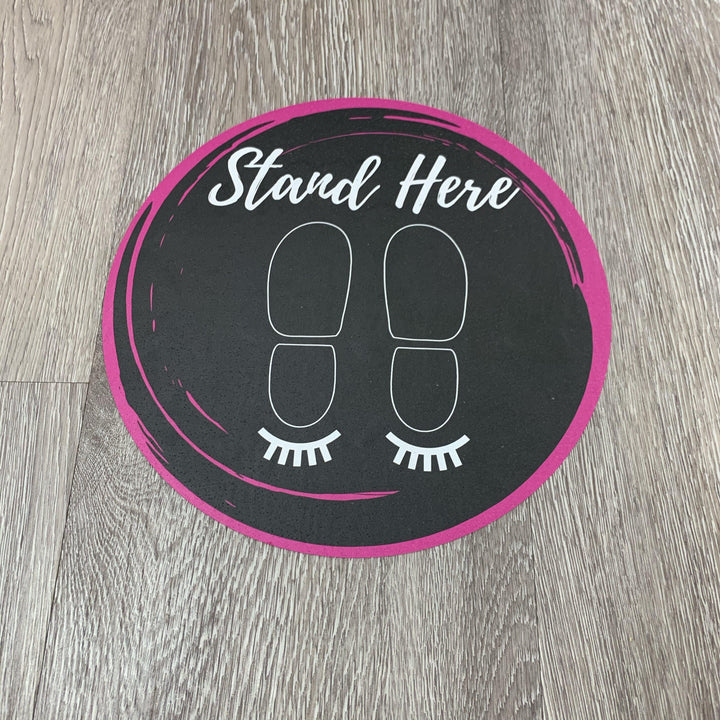 a black and pink Lash Tribe Social Distancing Floor Sticker that says stand here.
