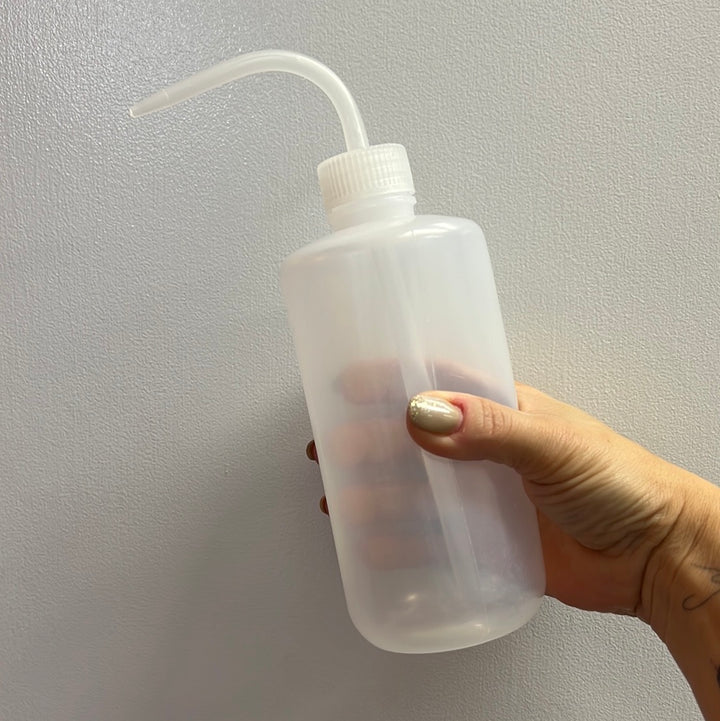 a person holding up a Lash Tribe Plastic Squeeze Water Bottle with a straw.