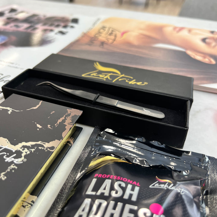 a box of Lash Tribe MEGA Volume Lashes Starter Kit and a magazine on a table.