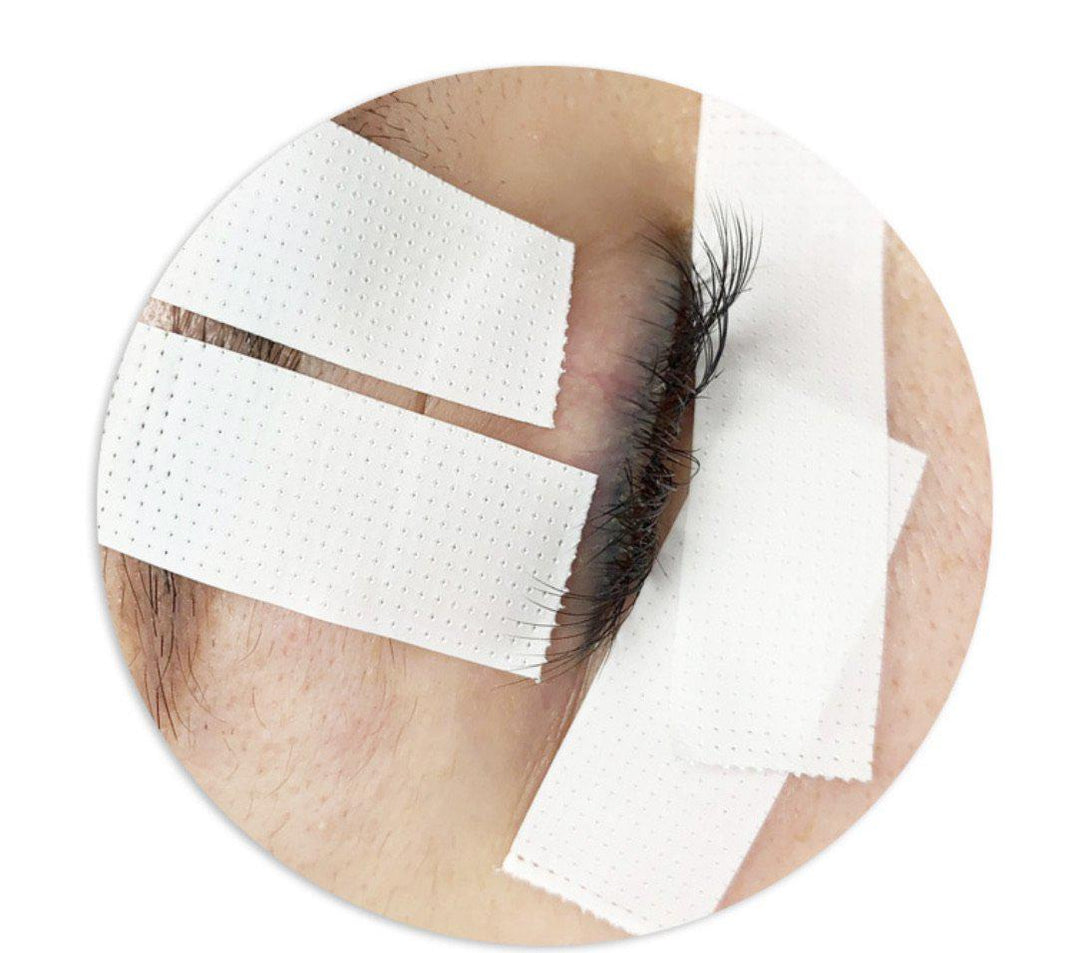 A woman's eye with a Lash Tribe Japanese Comfort Lash Tape | Breathable Tape | Eyelash Extensions Tape bandage on it.