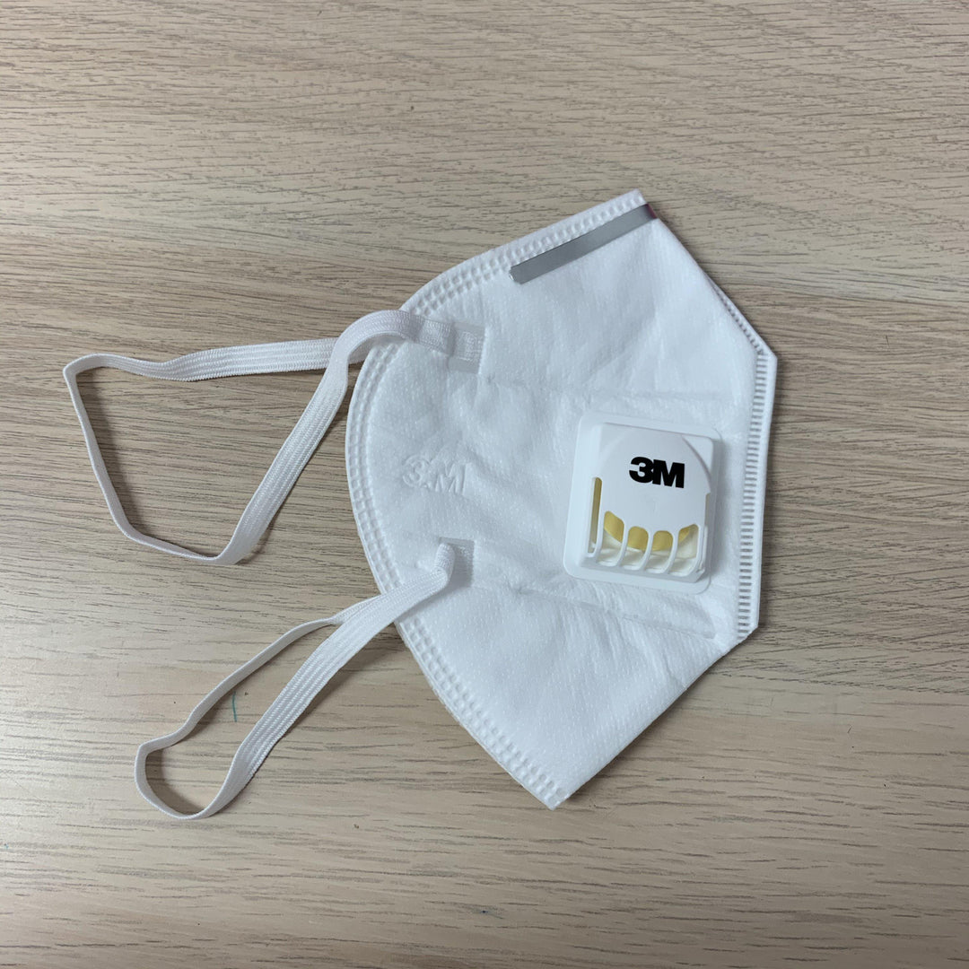 a 3M KN95 Medical Grade Mask with Valve by Lash Tribe on a wooden table.