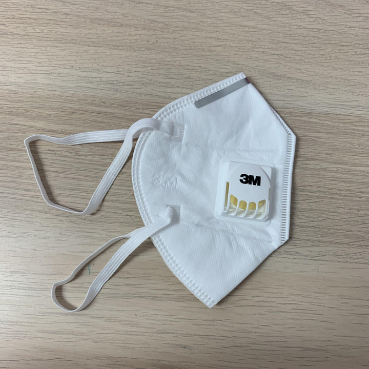 a 3M KN95 Medical Grade Mask with Valve by Lash Tribe on a wooden table.